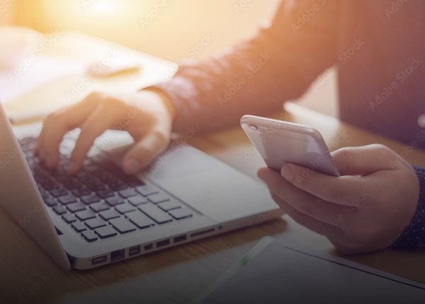 Person mit Handy und Laptop